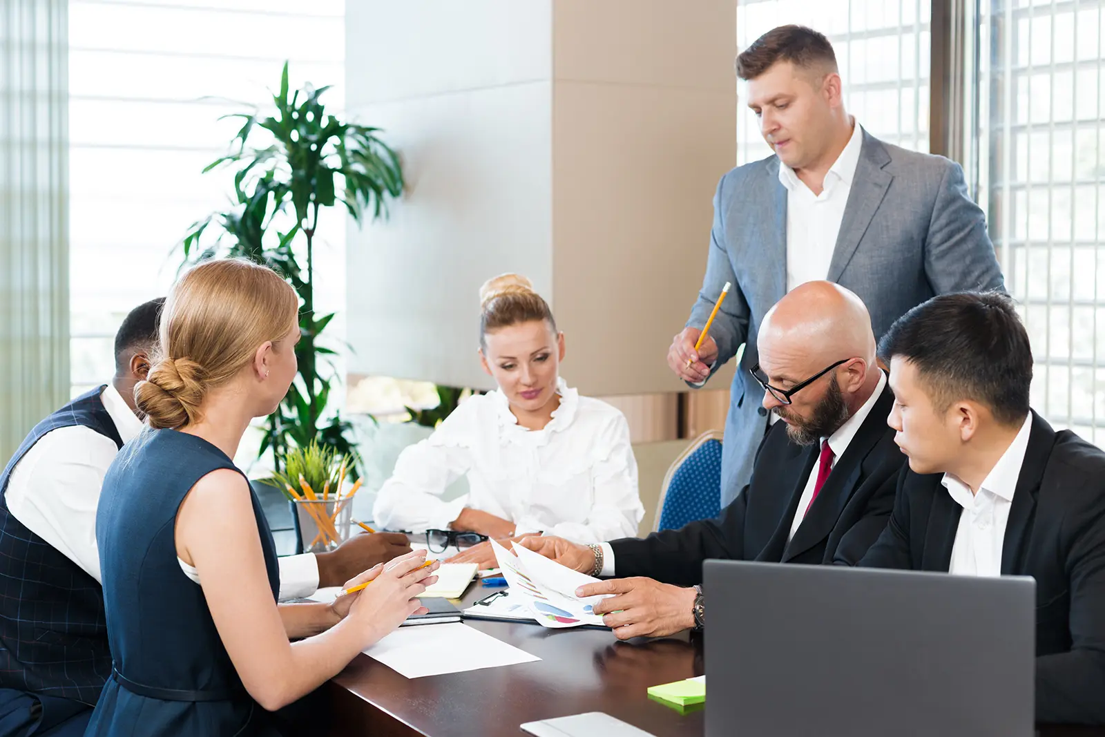 Group of professionals collaborate in a bright office, sharing ideas over documents and notes.