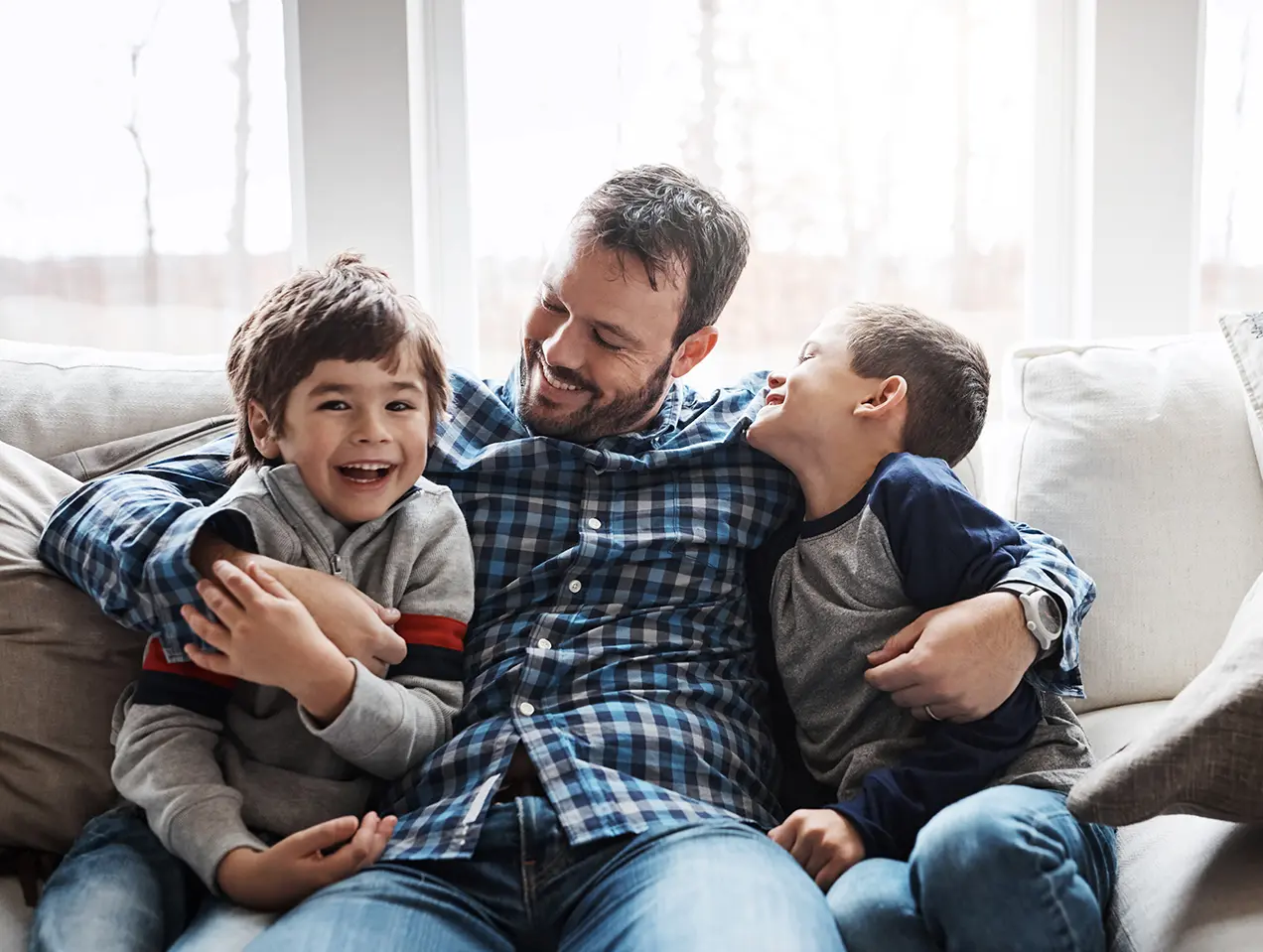 Hug, happy and portrait of father with children on the sofa for love, care and relax in family home. Smile, funny and dad with boy kids for quality time, affection and comedy on the couch of a house.