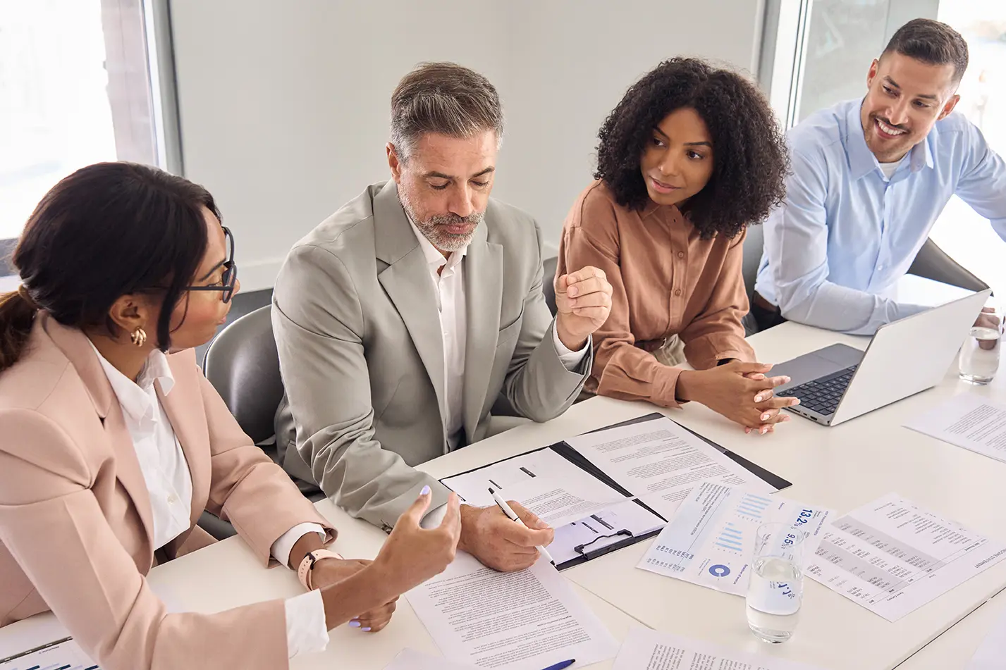 Busy older Latin business man investor checking bank document at office team meeting with financial law experts team thinking of risks managing corporate paperwork. Consultancy advisory services.