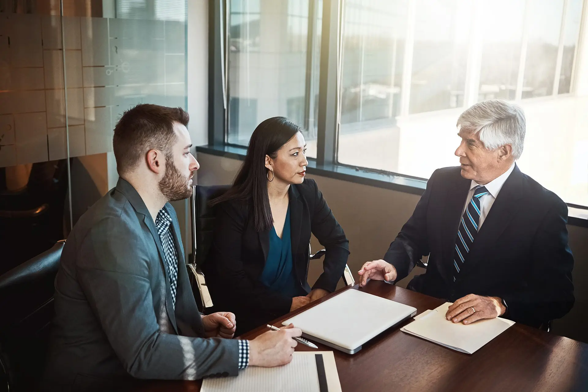 Men, woman and lawyer with documents in boardroom for discussion, negotiation and legal compliance. People, business owner and attorney with paperwork, laptop and listen to advice for company growth.