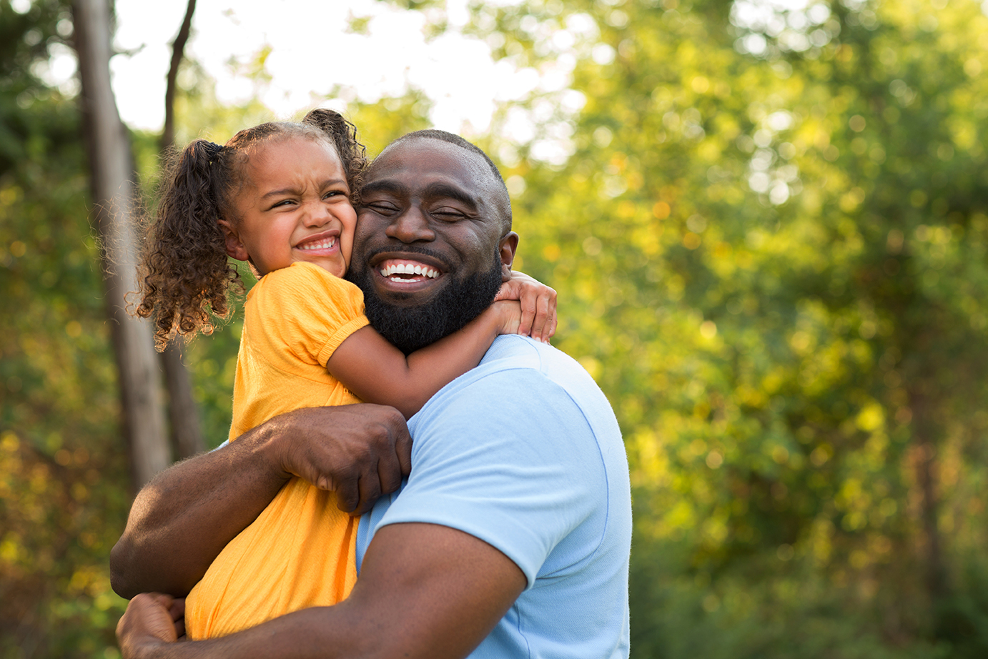Father and his daughter laughing and playing outside.